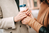 Man holds a coffee cup and hands of woman outdoors