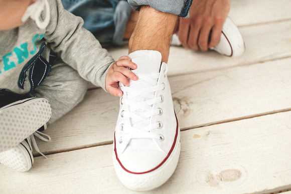 Baby hand on the shoe of the father close-up