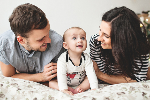 Happy young father mother and baby boy lying on bed